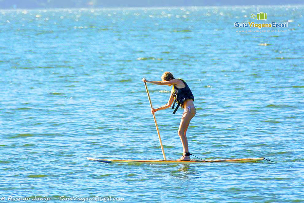 Imagem de uma menina praticando stand up paddle.